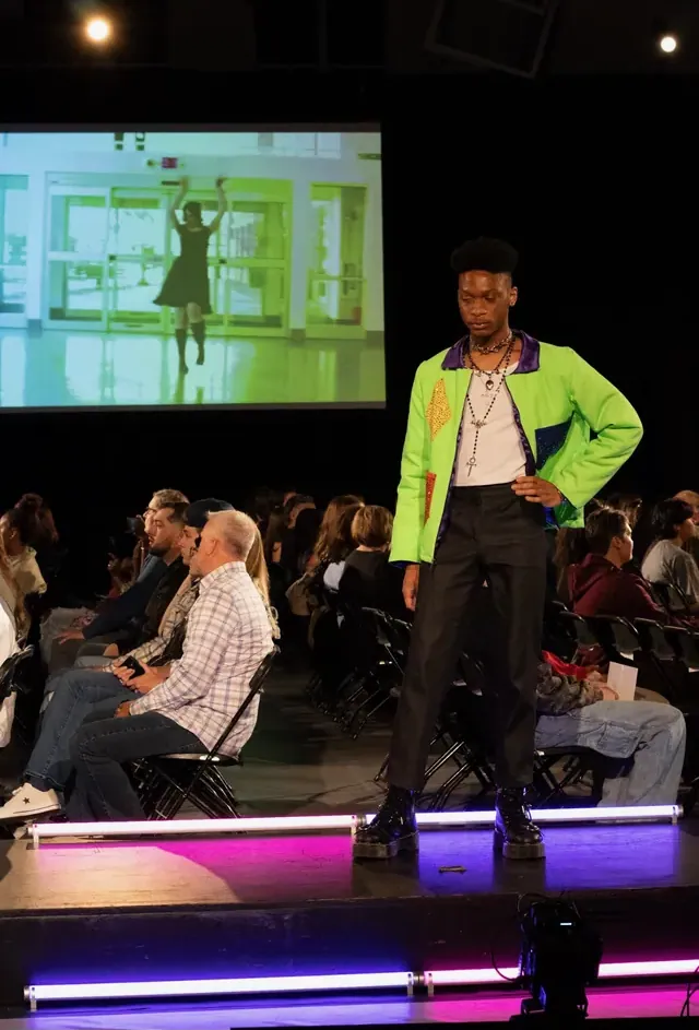 Model in a neon green appliquéd jacket on the runway